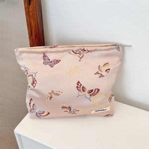 Detail of floral butterfly jacquard fabric and silver metal zipper on a pink shoulder bag