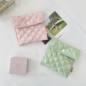 Dettaglio della trama a cuore trapuntata su pochette in tessuto rosa e verde menta