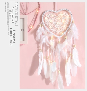 Detail of white heart dreamcatcher with glowing LED lights and soft hanging feathers