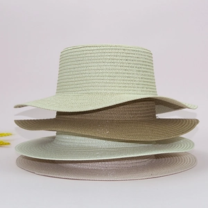 Stacked woven paper straw hat bases in light green, khaki, beige, and soft pink shades