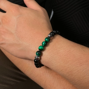 Detail of men's stainless steel bracelet with black beads and green tiger eye stones