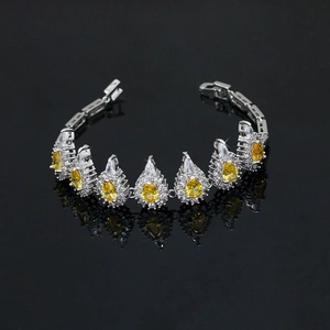 Macro view of silver bracelet with yellow teardrop gems and crystals on black background