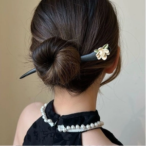 Detail of wooden hair stick with white flower and green leaf in an elegant bun