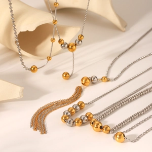 Detail of 18K gold stainless steel necklace featuring mixed beads and a tassel pendant