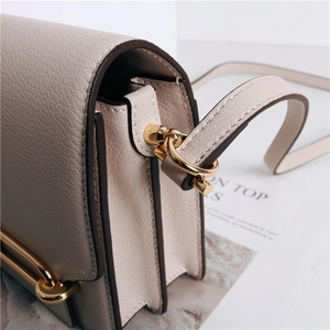 Dettaglio della borsa in pelle beige con motivo litchi e fibbie in metallo dorato lucido