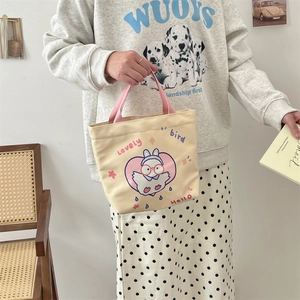 Detail of canvas tote bag with cute rabbit print and pink handle held by a model