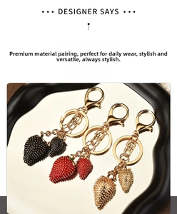 Detail view of strawberry metal keychains with textured enamel in red, black, and gold