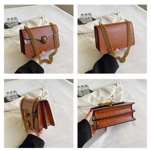 Detail view of brown crocodile texture handbag with gold chain and lion head hardware