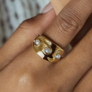 Elegant 18K gold plated wide stainless steel ring with three white pearls on a model hand
