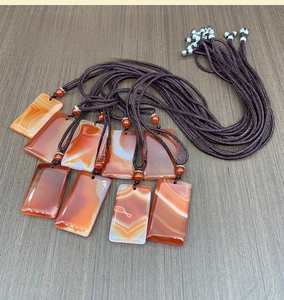 Macro shot of natural red agate pendants with polished finish and woven neck cords