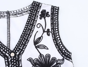Close-up of bohemian V-neckline with black floral embroidery and lace detailing