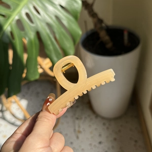 Detail of cream apricot hair claw clip with golden spring mechanism and matte finish