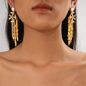 Detail of 18K gold-plated tassel earrings with white pearls and crystals on a model
