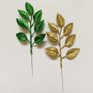 Detail of glittered artificial Christmas leaves in green and gold on white background