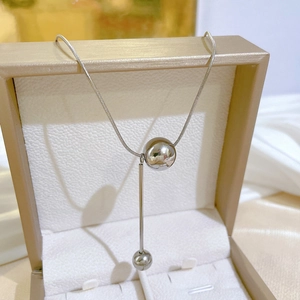 Silver titanium steel tassel necklace with round pendants inside a beige gift box