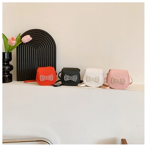 Close-up of four candy-colored mini purses in red, black, white, and pink with pearl bows