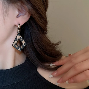 Vue latérale d'une femme portant des boucles d'oreilles géométriques léopard pour l'automne