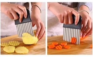 Close-up of wavy stainless steel cutter slicing potatoes and carrots on a wood board