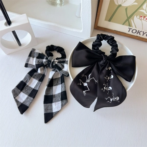 Detail of bow hair scrunchies in black and white plaid and skull patterns on a white table