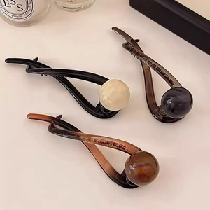 Three minimalist twist hair clips with large pearl accents in black, brown and amber shades