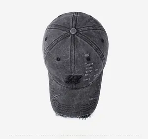 Detail view of RY letter embroidery and distressed holes on washed grey denim baseball cap