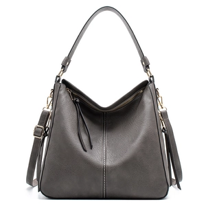 Detail view of dark grey pebble leather handbag with V-shaped zipper and gold hardware
