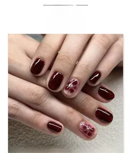 Detailed view of short round press-on nails with dark red amber finish and floral pearl design