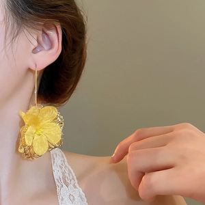 Gros plan de boucles d'oreilles fleur jaune avec cadre en métal doré sur modèle