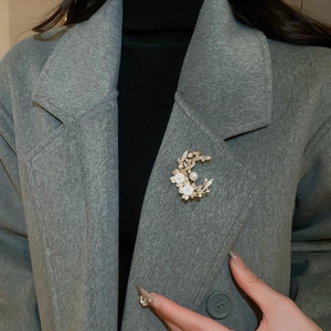 Macro detail of crescent flower brooch with pearls and zircon on a grey wool coat