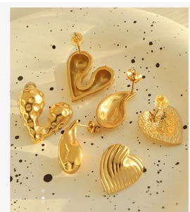 Detailed view of French vintage gold heart and teardrop earrings on a ceramic dish