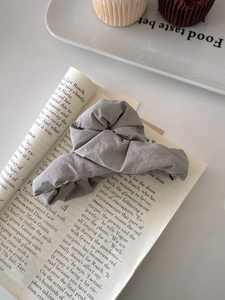 Detail of light grey fabric hair scrunchie with pleated texture on a fashion magazine