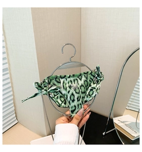 Detail of green leopard print bikini style crossbody bag hanging on a metal hanger
