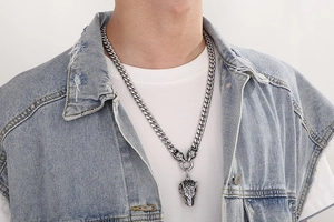 Close-up of titanium steel wolf head pendant on a thick curb chain worn by a model