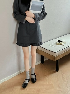 Detail of grey mesh crew socks paired with black Mary Jane shoes and a ruffle skirt