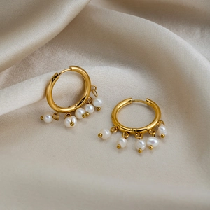 Detail of 18K gold plated hoop earrings with five freshwater pearl charms on satin fabric