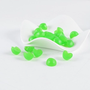 Close-up of translucent green PVC mini apple craft material on a wavy white tray