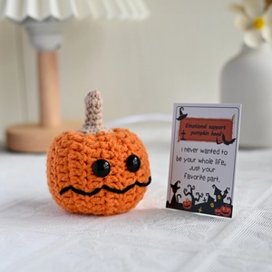 Crochet pumpkin plush with Emotional Support card on white textured surface
