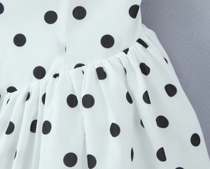 Détail de robe blanche à pois noirs avec plis à la taille et texture de mousseline
