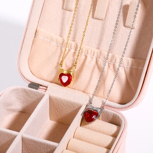 Gold and silver heart necklaces with red zircon pendants in a pink jewelry box