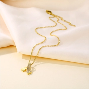 Elegant gold bow necklace with clear zircon stones on soft beige textured fabric