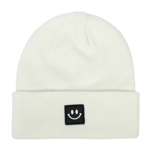 Detail of white ribbed knit beanie featuring a black square woven patch with a smiley face
