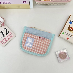 Close-up of quilted cloth coin purse with cute bear patch and blue checkered pattern