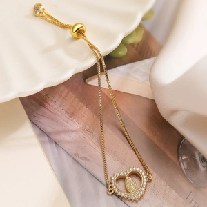 Gold-plated heart bracelet with Virgin Mary icon and zircon inlays on a white tray