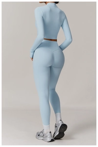 Detail of light blue high-waisted yoga leggings and long sleeve zip crop top with slim fit