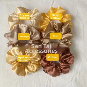 Detail view of large satin scrunchies in cream, champagne, and coffee earth tones