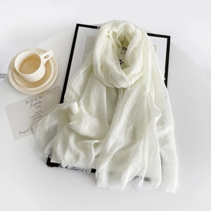 Detail of white cotton linen scarf with soft fringe edges and breathable woven texture