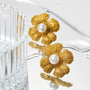 Vintage gold flower earrings with pearls and brushed texture on mirror reflection