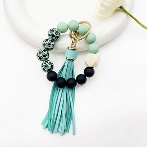 Detail of silicone beads keychain with mint tassel and leopard print on white tray