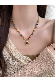 Détail d'un collier bohème vintage avec pierres d'œil de tigre et pendentif doré
