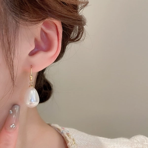 French vintage large teardrop pearl earrings with gold hooks on a side-profile model